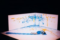 David Wampach malt mit dem Bauch eine blaue Bahn. 